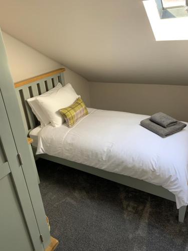 um quarto com uma cama com lençóis brancos e almofadas em The Tweed in the centre of Melrose em Melrose