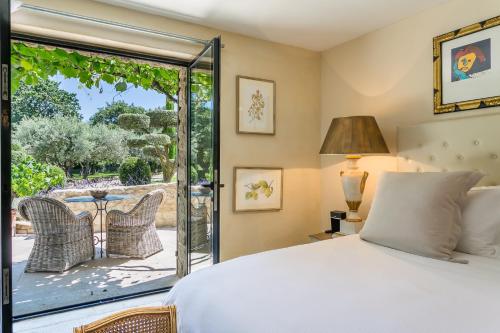 a bedroom with a bed and a glass door leading to a patio at Domaine Les Roullets in Oppède