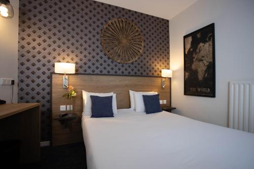 a hotel room with a large bed with blue pillows at Hotel Continental in Angers