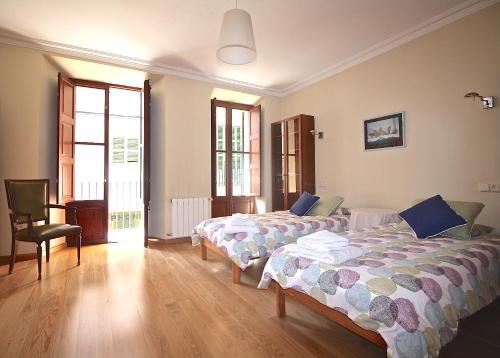 a bedroom with two beds and a chair at Casa Carrer de Bonany in Sóller
