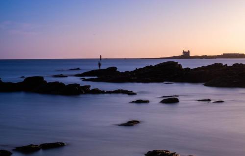 a beach with rocks in the water at sunset at Hôtel La Petite Sirène Quiberon in Quiberon