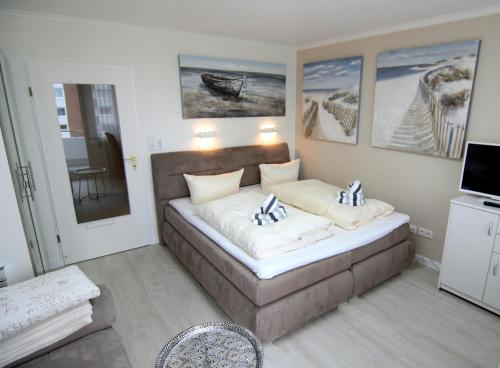 ein Schlafzimmer mit einem Sofa und Gemälden an der Wand in der Unterkunft Arielle in Westerland