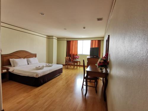 una camera d'albergo con letto, tavolo e scrivania di Morakot Twin Chumphon a Chumphon