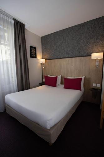 a large bed in a hotel room with red pillows at Hotel Continental in Angers