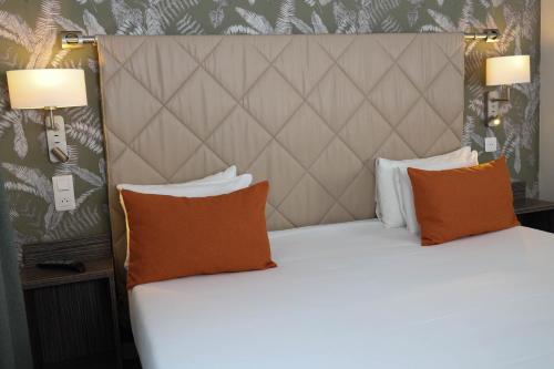 a large bed with two pillows and two lamps at Hotel Continental in Angers