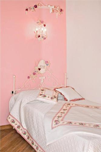 a pink bedroom with a bed and a chandelier at La Maison Rosa Stella in Lucera