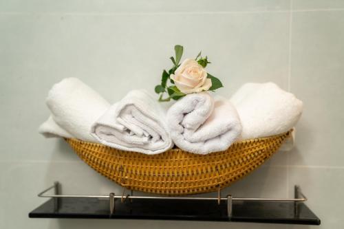 a basket with towels and a rose on a wall at Harmony Homestay in Da Nang