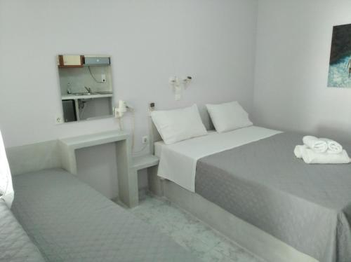 a white bedroom with a bed and a sink at Amorgaia 1 in Katapola