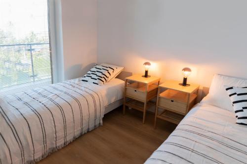 a bedroom with two beds and two night stands with lamps at Apartamenty na Wzgórzu in Bochnia