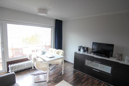 a living room with a table and chairs and a television at Nina in Wenningstedt