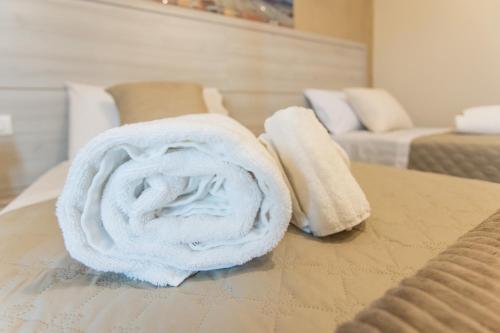 a pile of white towels sitting on top of a bed at Oasi Perla Del Mare Rooms in Aci Castello