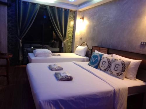 una camera con 2 letti con lenzuola e cuscini bianchi di WEE HOSTEL a Kanchanaburi