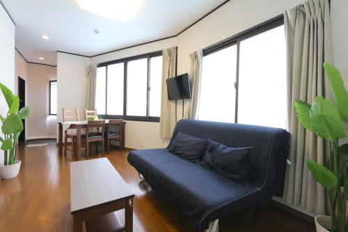 a living room with a blue couch and a table at Liz4 Guest House Liz Nakazakicho in Osaka