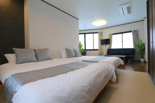 a bedroom with two beds and a chair at Liz4 Guest House Liz Nakazakicho in Osaka