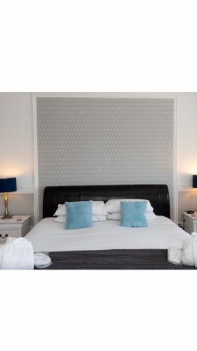 a large bed with two blue pillows on it at MacKays in Oban