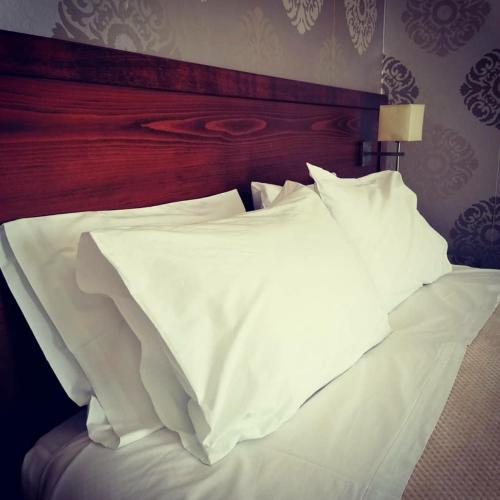 a white bed with a wooden headboard and white pillows at Anemolia Studios in Loutra Edipsou
