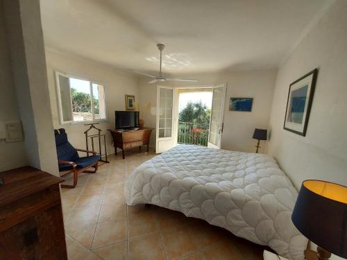 a bedroom with a bed and a desk and windows at Villa Le Sud in Les Issambres