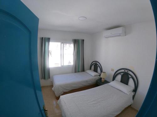 プエルト・デ・モガンにあるApartamentos Ernestoのベッド2台と窓が備わる客室です。