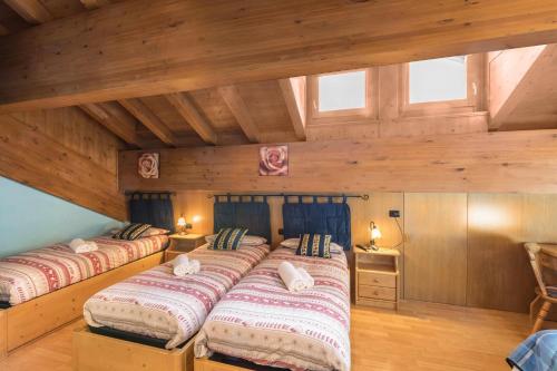 twee bedden in een kamer met houten wanden en ramen bij Nadir - Casa Azzurra in Livigno