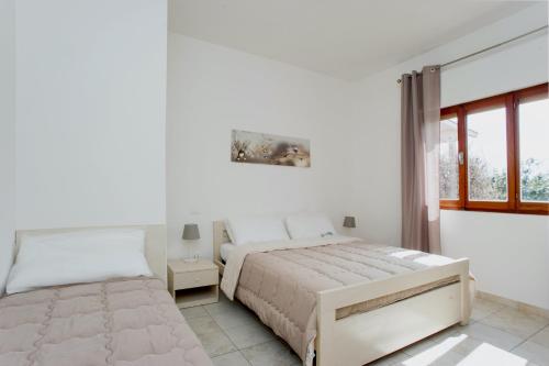 a white bedroom with a bed and a window at Il Caubbio in Lacona