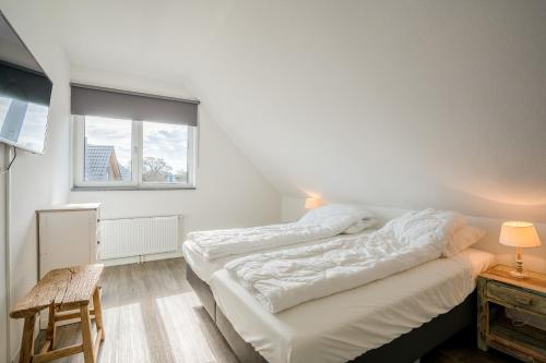 twee bedden in een kamer met een raam bij Hoogelandt 106F in De Koog
