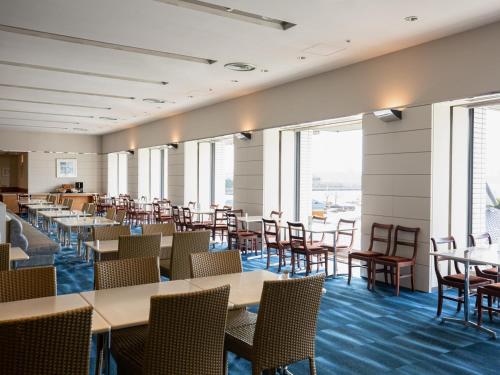 a dining room with tables and chairs and windows at Hotel Okura Kobe in Kobe