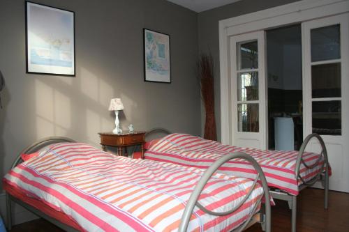 ein Schlafzimmer mit einem Bett mit einer gestreiften Decke und einem Fenster in der Unterkunft La Maison d'Antoine in Maison-Ponthieu