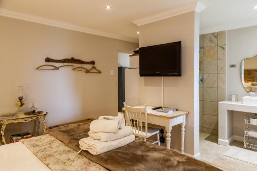 a room with a tv and a desk and a bed at Nerf-af ROOMS at Onrus , Hermanus in Hermanus