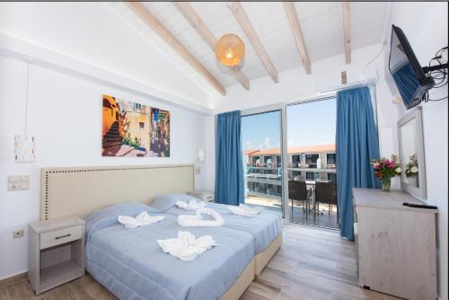 um quarto com uma cama com lençóis azuis e uma varanda em Angela Beach Hotel & Apts em Roda
