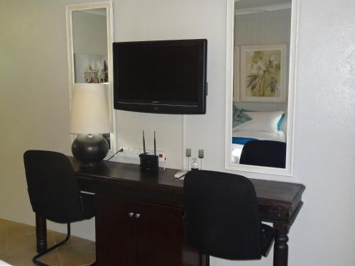 a bedroom with a desk with a television and a mirror at Waterglen Guest Lodge in Rustenburg