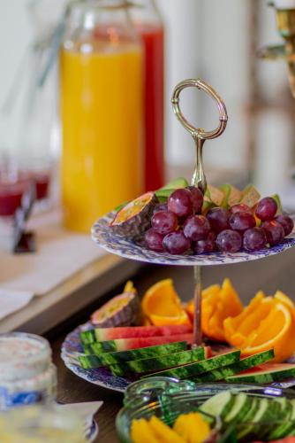 a plate of fruit on a counter with a tray of grapes and oranges at Rosenhill Bed & Breakfast in Grebbestad