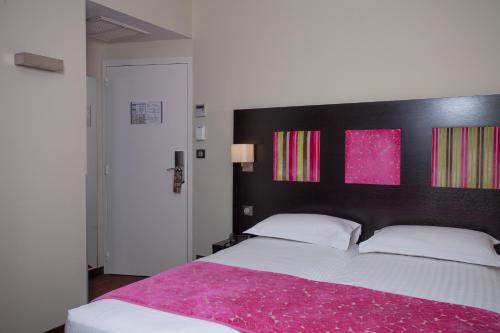 a bedroom with a large bed with a pink blanket at Hôtel Baptistin in Le Lavandou