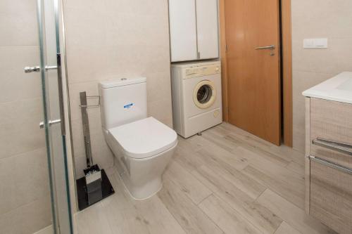 a bathroom with a toilet and a washer and dryer at APCOSTAS Los Iris - familiar in Playa de Gandia