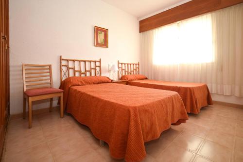 a bedroom with two beds and a chair and a window at APCOSTAS Los Iris - familiar in Playa de Gandia