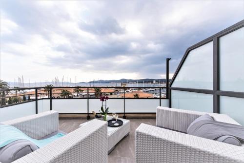 a balcony with white furniture and a view of the ocean at Hôtel Baptistin in Le Lavandou