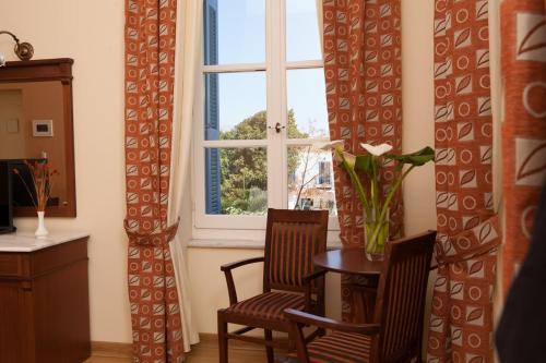 a dining room with a table and two chairs and a window at Egli Hotel in Andros