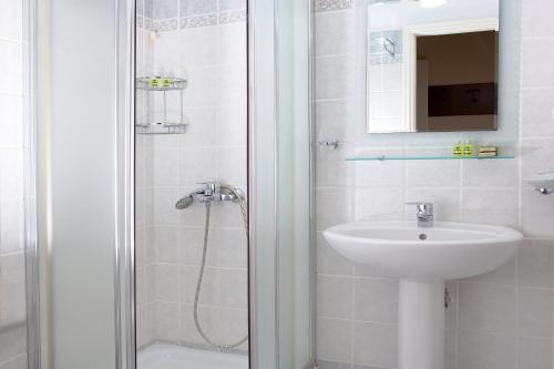 a white bathroom with a sink and a shower at Egli Hotel in Andros