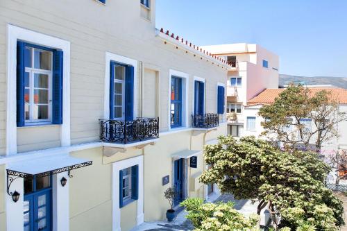 a row of white houses with blue windows at Egli Hotel in Andros