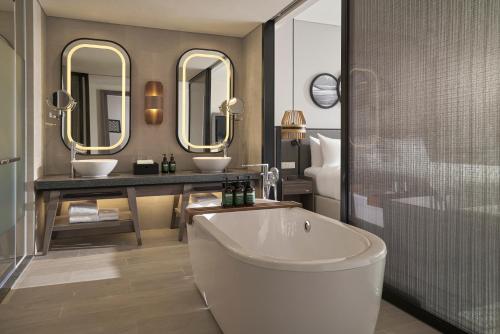 a bathroom with a tub and two sinks and mirrors at Crowne Plaza Phu Quoc Starbay by IHG in Phu Quoc