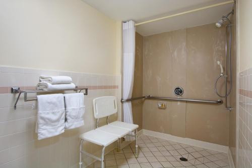 a bathroom with a shower and a chair and towels at Days Inn by Wyndham Longview South in Longview