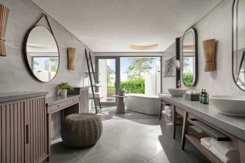 a bathroom with two sinks and a tub and mirrors at Crowne Plaza Phu Quoc Starbay by IHG in Phu Quoc