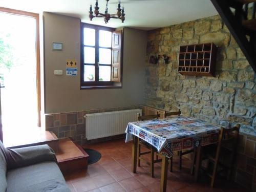 a living room with a table and a stone wall at Apartamentos Rurales El Gobernador in Villaviciosa