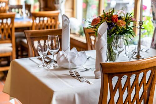a table with a white table cloth with wine glasses and flowers at Hotel Blaue Gams ***S in Ettal
