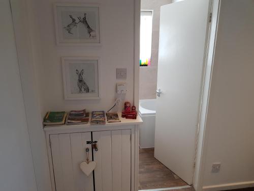 a room with a small white cabinet with books on it at Bowness On Windermere, Lovely Apartment for 4 With Parking in Bowness-on-Windermere