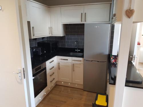 a kitchen with white cabinets and a stainless steel refrigerator at Bowness On Windermere, Lovely Apartment for 4 With Parking in Bowness-on-Windermere