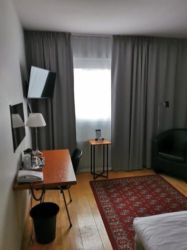 a hotel room with a desk and a bed and a window at Best Western Hotel Botnia in Umeå