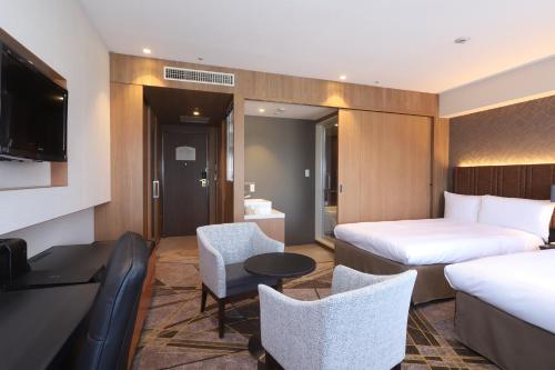 a hotel room with two beds and a table and chairs at ANA Crowne Plaza Hotel Kushiro by IHG in Kushiro