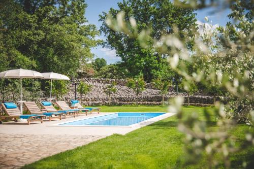 - une piscine avec des chaises longues et un parasol dans l'établissement Village Villa „ M „, à Malinska