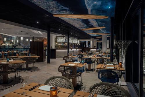 a restaurant with wooden tables and chairs and a bar at Inntel Hotels Den Haag Marina Beach in Scheveningen