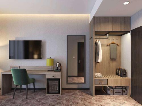 a room with a desk and a green chair at Mercure Bialystok in Białystok